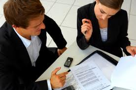 Two people at a desk discussing a document